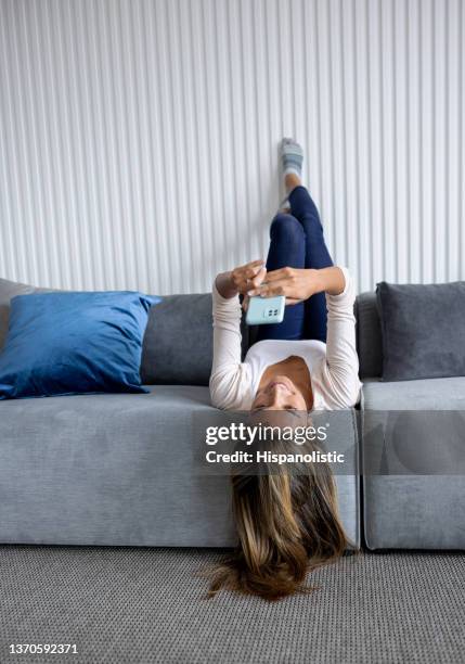 happy woman at home texting on her cell phone - geographical locations stock pictures, royalty-free photos & images