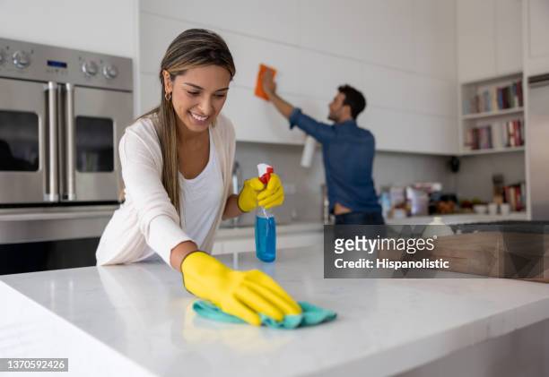 feliz pareja en casa limpiando la cocina - home cleaning fotografías e imágenes de stock