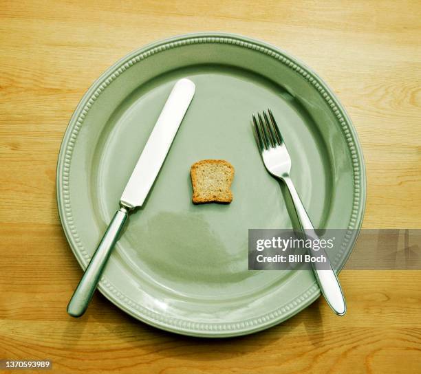 dieting concept—very small bread on green plate—part of a series - magersucht stock-fotos und bilder