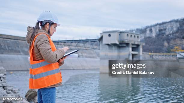 ingenieurin, die im staudamm arbeitet. ökologieorientiert. erneuerbare energiesysteme. - reservoir stock-fotos und bilder