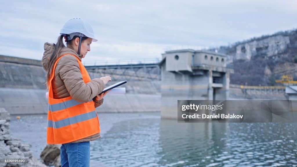 Female engineer working in hydroelectric dam. Ecology orientated. Renewable energy systems.