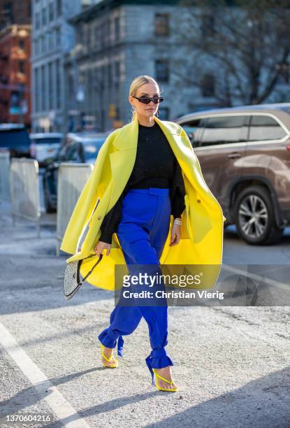 Leonie Hanne seen wearing blue pants, yellow coat, Prada bag, yellow heels, black jumper outside Bevza during New York Fashion Week on February 14,...