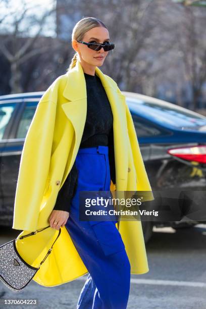 Leonie Hanne seen wearing blue pants, yellow coat, Prada bag, yellow heels, black jumper outside Bevza during New York Fashion Week on February 14,...