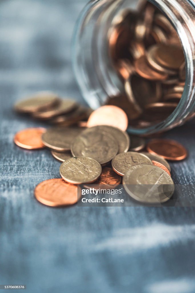 Loose change spilling from a savings jar of money. Finance and savings concept