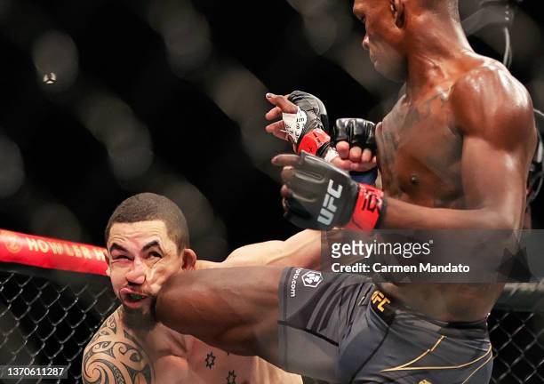 Israel Adesanya of Nigeria knees Robert Whittaker of Australia in their middleweight championship fight during UFC 271 at Toyota Center on February...