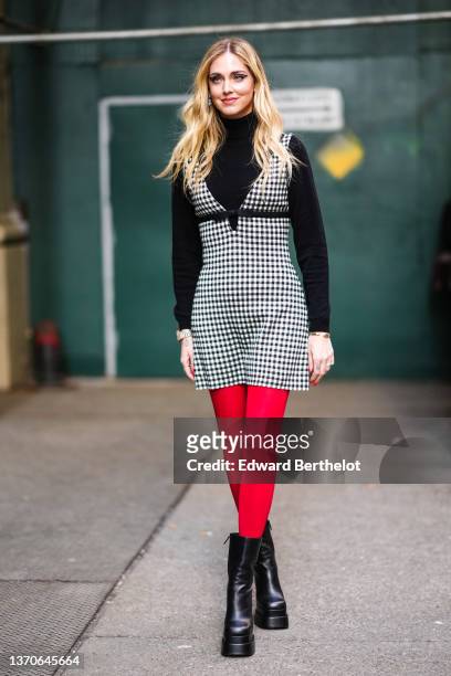 Chiara Ferragni wears silver and large rhinestones pendant earrings, a black turtleneck wool pullover, a black and white checkered print pattern...