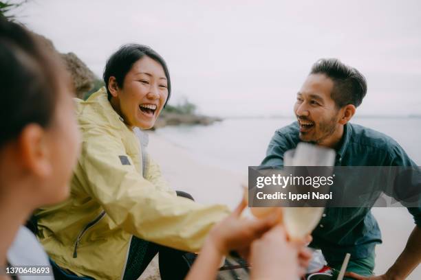 cheerful people having a toast on beach at dusk - japanese couple beach stock pictures, royalty-free photos & images