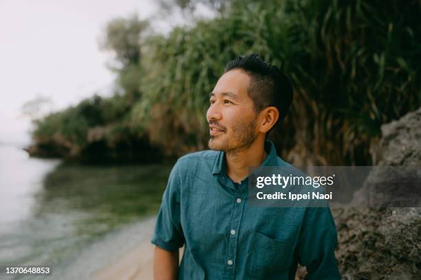 portrait of japanese man pondering on beach at dusk - shallow depth of field people beach stock pictures, royalty-free photos & images