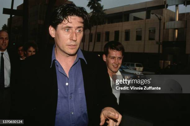Irish actor Gabriel Byrne, wearing a black jacket over a blue shirt, attends an event, circa 1995.