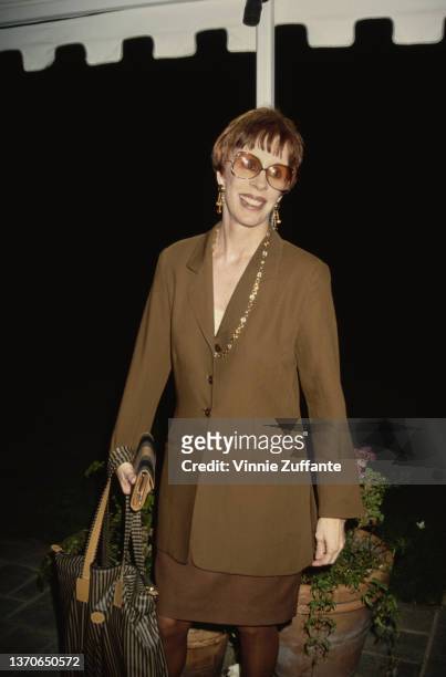 American comedian and actress Carol Burnett, wearing a brown suit with a long necklace and sunglasses, attends an event, 1994.