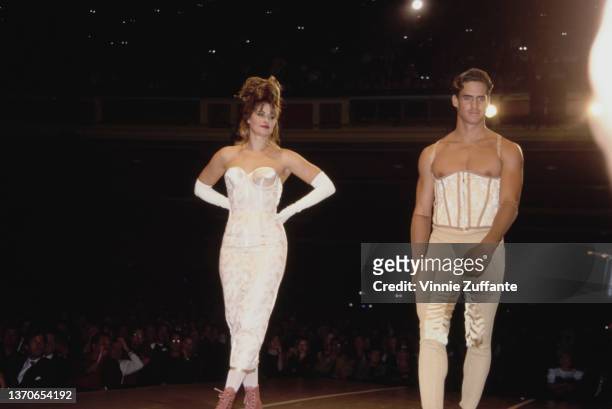 American actress Lorraine Bracco, wearing a white dress with white evening gloves, and a male model on the catwalk during the Jean Paul Gaultier...