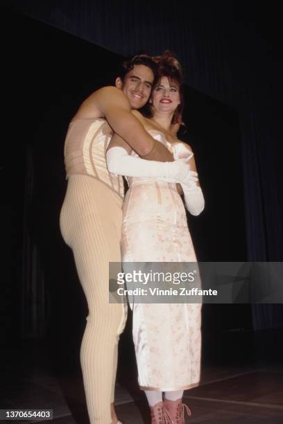 Male model embraces American actress Lorraine Bracco, wearing a white dress with white evening gloves, on the catwalk during the Jean Paul Gaultier...