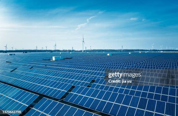 solar power stations in plain areas, large blue solar panels and huge wind turbines. creative pictures. - solar farm stockfoto's en -beelden