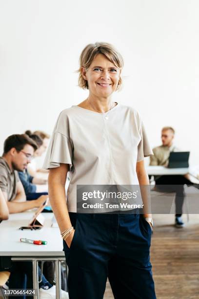 portrait of seminar tutor in her classroom - einzelne frau über 40 stock-fotos und bilder