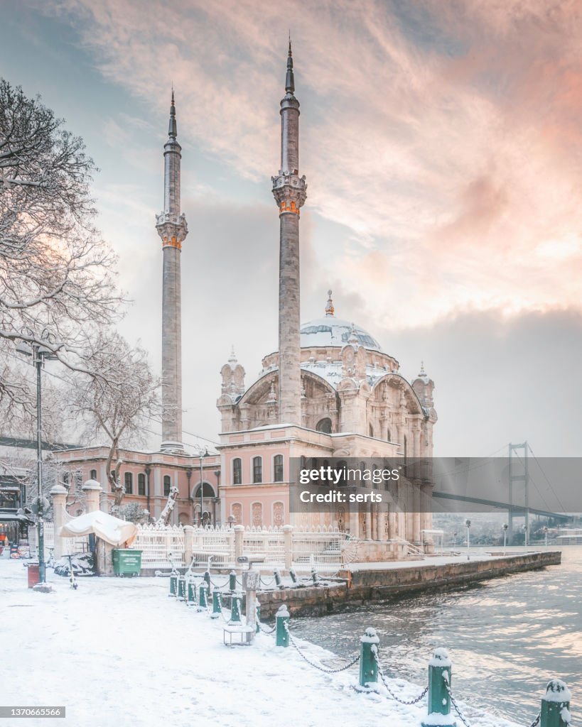 Snowy day in Istanbul, Turkiye. Ortakoy Mosque view with Bosphorus Bridge.