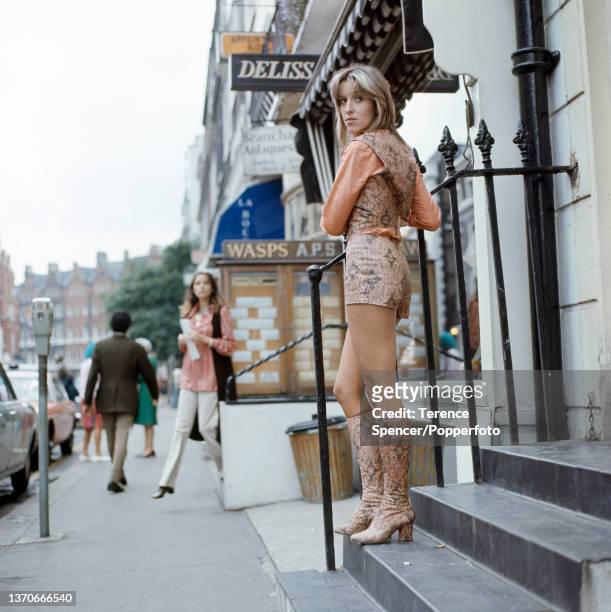 Fashionable young woman wearing printed hot pants and waistcoat and matching boots on the stylish shopping street Beauchamp Place in Knightsbridge,...