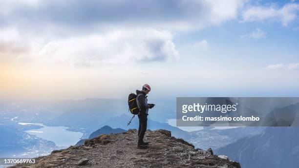 hiker checking smart-phone on top of the mountain - remote location cell phone stock pictures, royalty-free photos & images