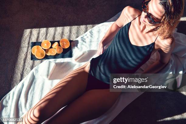 female beauty in underwear relaxing with orange slices and skincare products on floor spread towel - woman lipstick rearview stock pictures, royalty-free photos & images