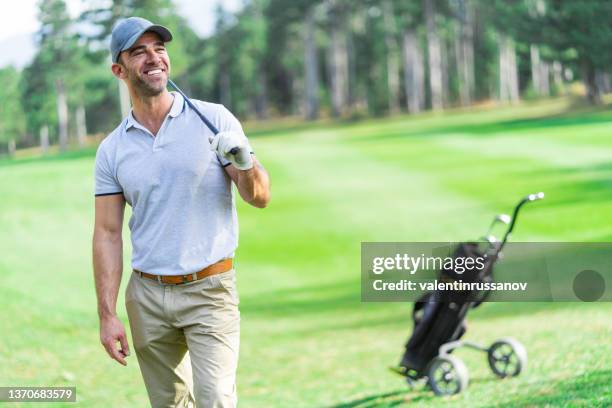 adult golf player standing leisurely on the golf course and looking away to the goal - golfer stock pictures, royalty-free photos & images