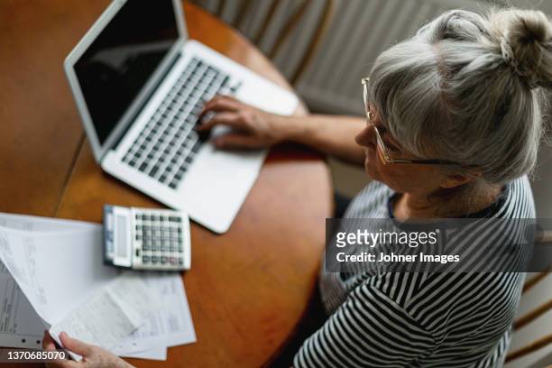 senior woman using laptop - calculadora fotografías e imágenes de stock