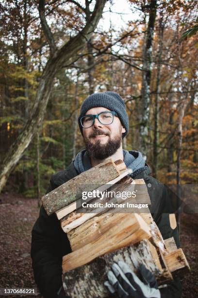 portrait of man carrying firewood in forest - brandhout stockfoto's en -beelden