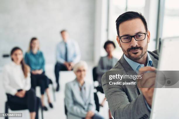 hombre de negocios escribiendo en una pizarra blanca durante una conferencia - rotafolio fotografías e imágenes de stock