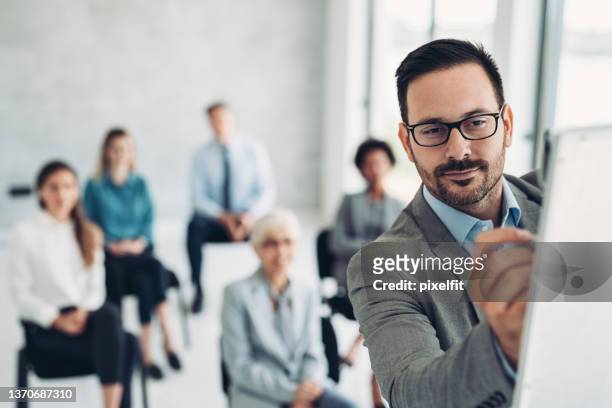 uomo d'affari che scrive su una lavagna bianca durante una conferenza - ricerca di mercato foto e immagini stock
