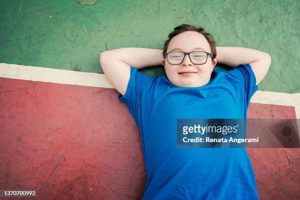 retrato de un niño con síndrome de down en una pista polideportiva - chubby boy fotografías e imágenes de stock