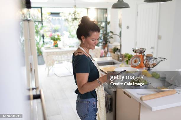 woman with smart phone cooking in kitchen - roll call stock pictures, royalty-free photos & images