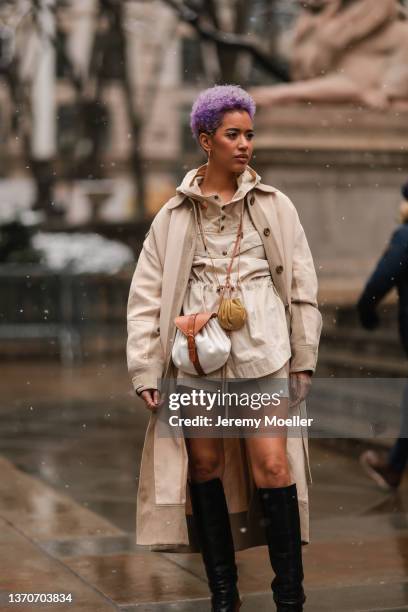 Actress Jasmin Savoy Brown is seen wearing an Ulla Johnson outfit including a beige overcoat, black knee high boots and a white and brown handbag...