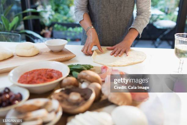 woman making fresh homemade pizza in kitchen - pizza ingredient stock pictures, royalty-free photos & images