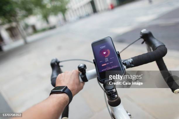 pov man riding bicycle with smart phone health monitor - caiaimage stock-fotos und bilder