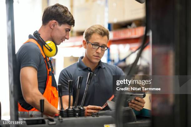 keeping up to date on health and safety requirements and forklift operating procedures. warehouse safety manager talking to forklift operator explaining about compliance with health and safety rules in a factory warehouse. - regulatory scrutiny stock pictures, royalty-free photos & images