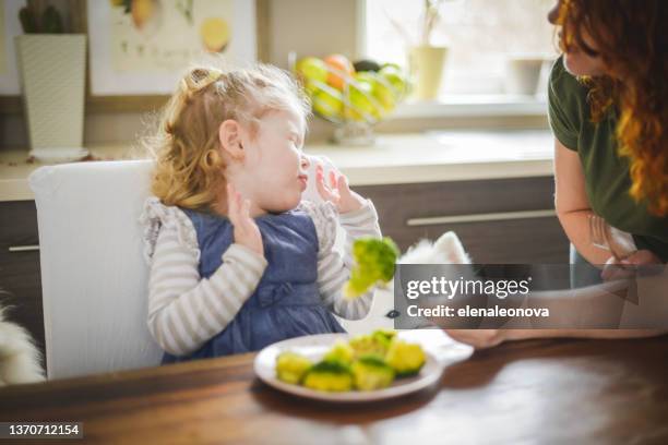 mutter und baby mädchen blond im häuslichen, essen brokkoli - refusing stock-fotos und bilder