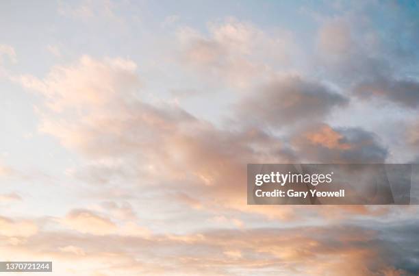 fluffy clouds at sunset - dramatische lucht stockfoto's en -beelden