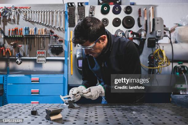 arbeiter mit schutzhandschuhen und brille mit einem bremssattel in einer werkstatt. - worktop stock-fotos und bilder