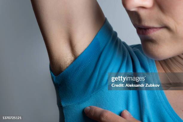 blonde hair under the armpits of a young woman. a girl in a bright t-shirt with sweat-soaked armpits. the concept of alternative choice, naturalness and natural beauty, authenticity of a person. active lifestyle, sports. - oksel stockfoto's en -beelden
