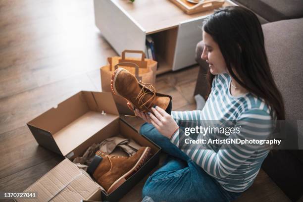 young woman unwrapping package at home. - package arrival stock pictures, royalty-free photos & images