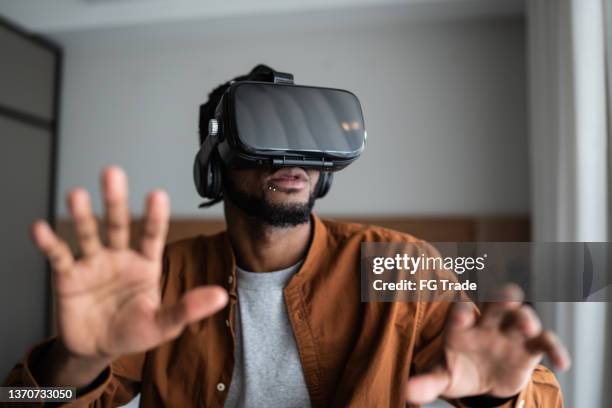 joven usando unas gafas de realidad virtual en casa - vida sencilla fotografías e imágenes de stock
