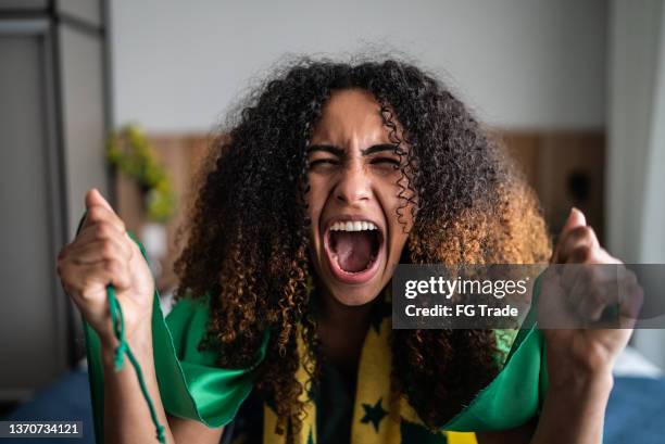 giovane donna eccitata che festeggia tenendo la bandiera verde - home game sport foto e immagini stock