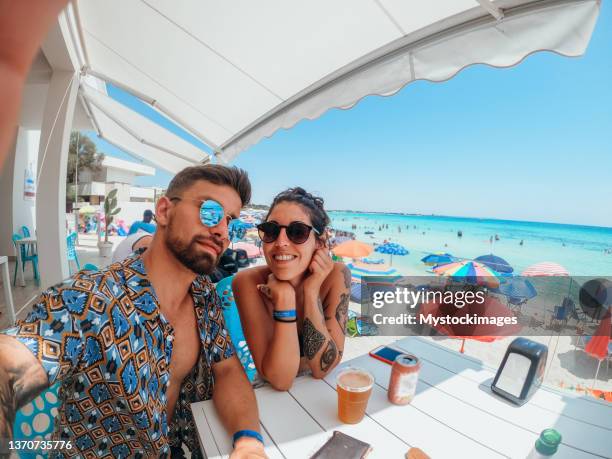 young couple take selfie in a cafe by the sea enjoying their summer vacations - couple on beach sunglasses stockfoto's en -beelden