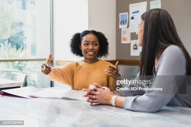 teen girl gestures while explaining something to female teacher - adult stockfoto's en -beelden