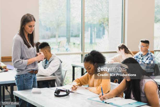 teacher walks around room as students take test - examination room bildbanksfoton och bilder