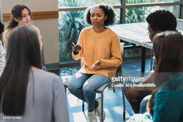 Female high school student gestures and shares in group therapy