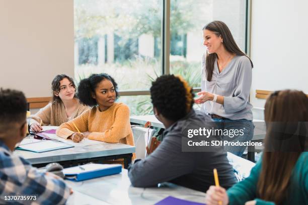 entspannte lehrerin spricht mit teenagern - neugierig und bildung stock-fotos und bilder