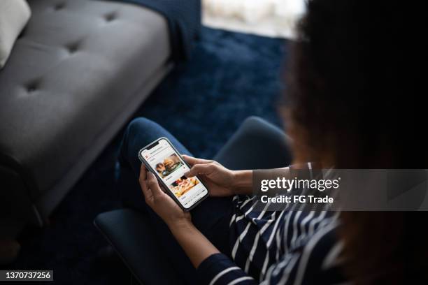young woman ordering food online with smartphone at home - encomendar imagens e fotografias de stock