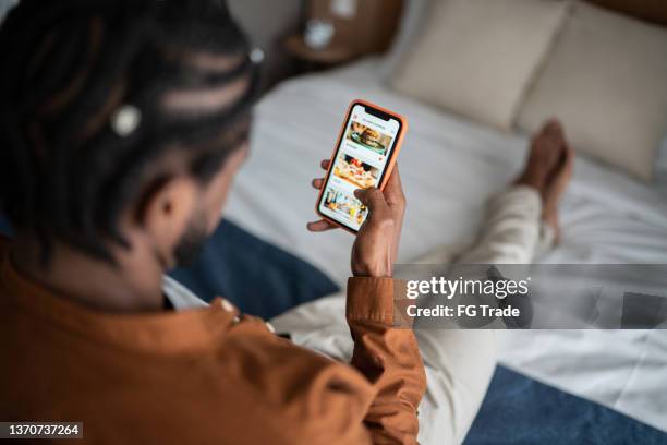 young man ordering food online with smartphone at home - demanding imagens e fotografias de stock