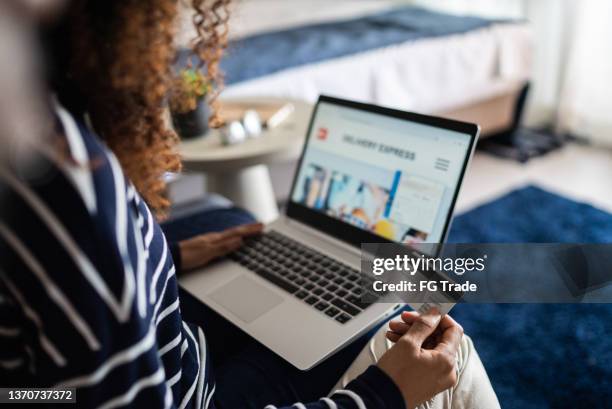 junge frau beim online-shopping mit dem laptop zu hause - elektronischer handel stock-fotos und bilder