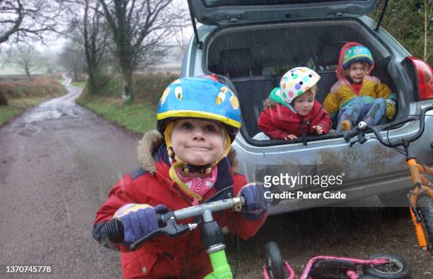 three children about to go cycling on a rainy day - car safety kids road stock pictures, royalty-free photos & images