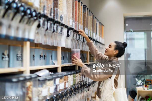 une jeune femme africaine fait ses courses dans un magasin zéro déchet - entreprise durable photos et images de collection